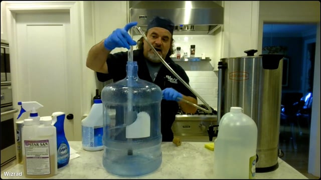Man in a kitchen with beer brewing equipment and cleaning products.