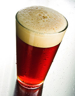 reddish hued clear amber beer with a tan head in a shaker pint glass
