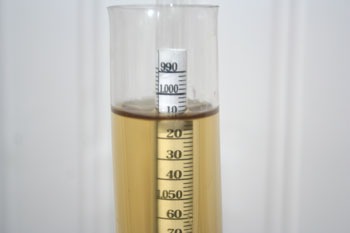 floating hydrometer reading roughly 1.010 specific gravity in a pale, golden beer