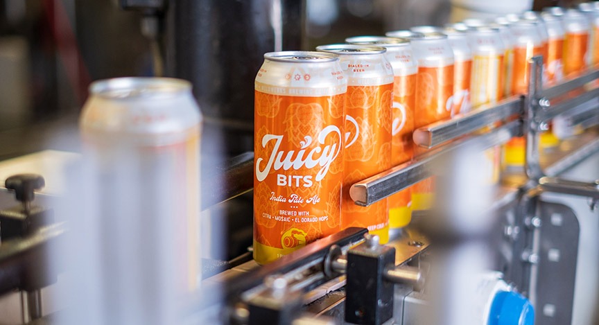 Cans of Juicy Bits beer on a conveyer.