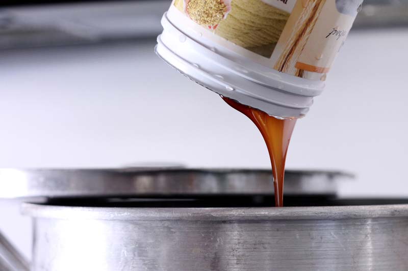 pouring liquid malt extract into a brew kettle