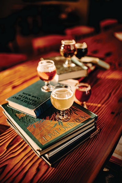 a flight of beer in small stemmed tulip glasses placed on classic library books