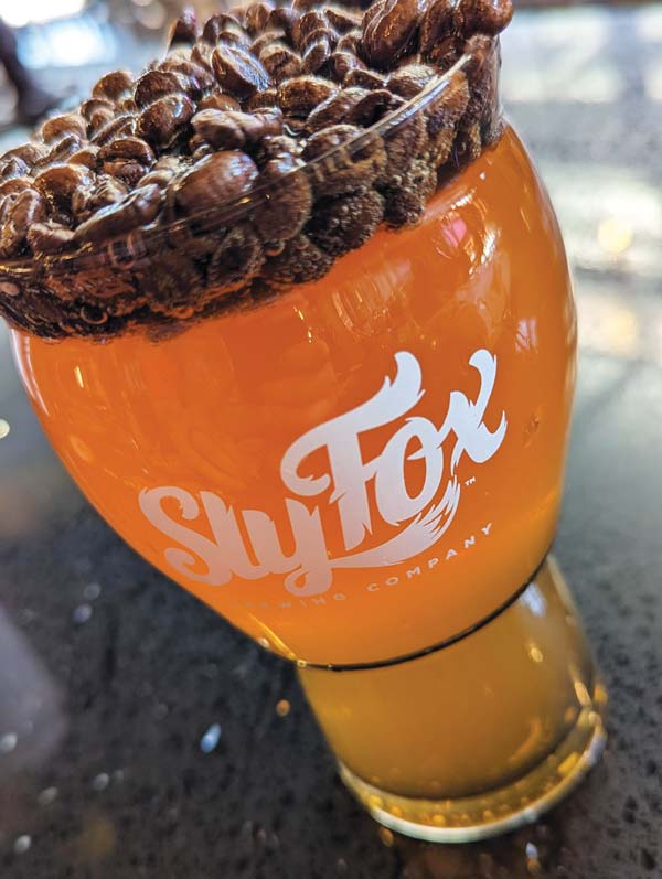 sly fox's morning coffee blonde ale with coffee beans floating on top in the pint glass