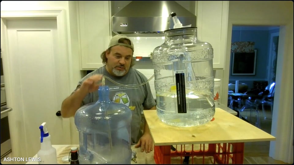 Man demonstrating how to siphon beer from brewing jugs.
